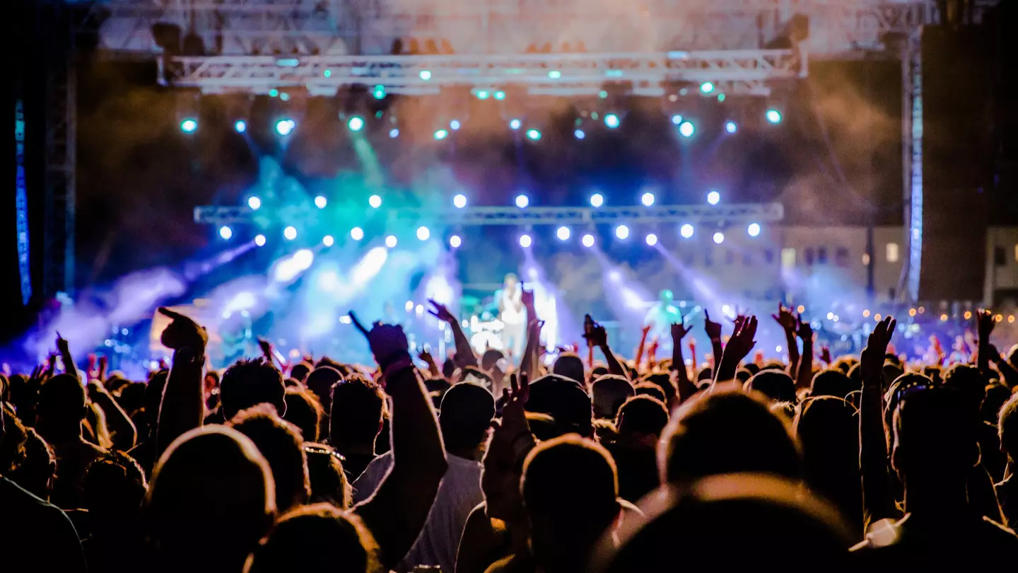 A view towards the stage over the heads of festival goers at night