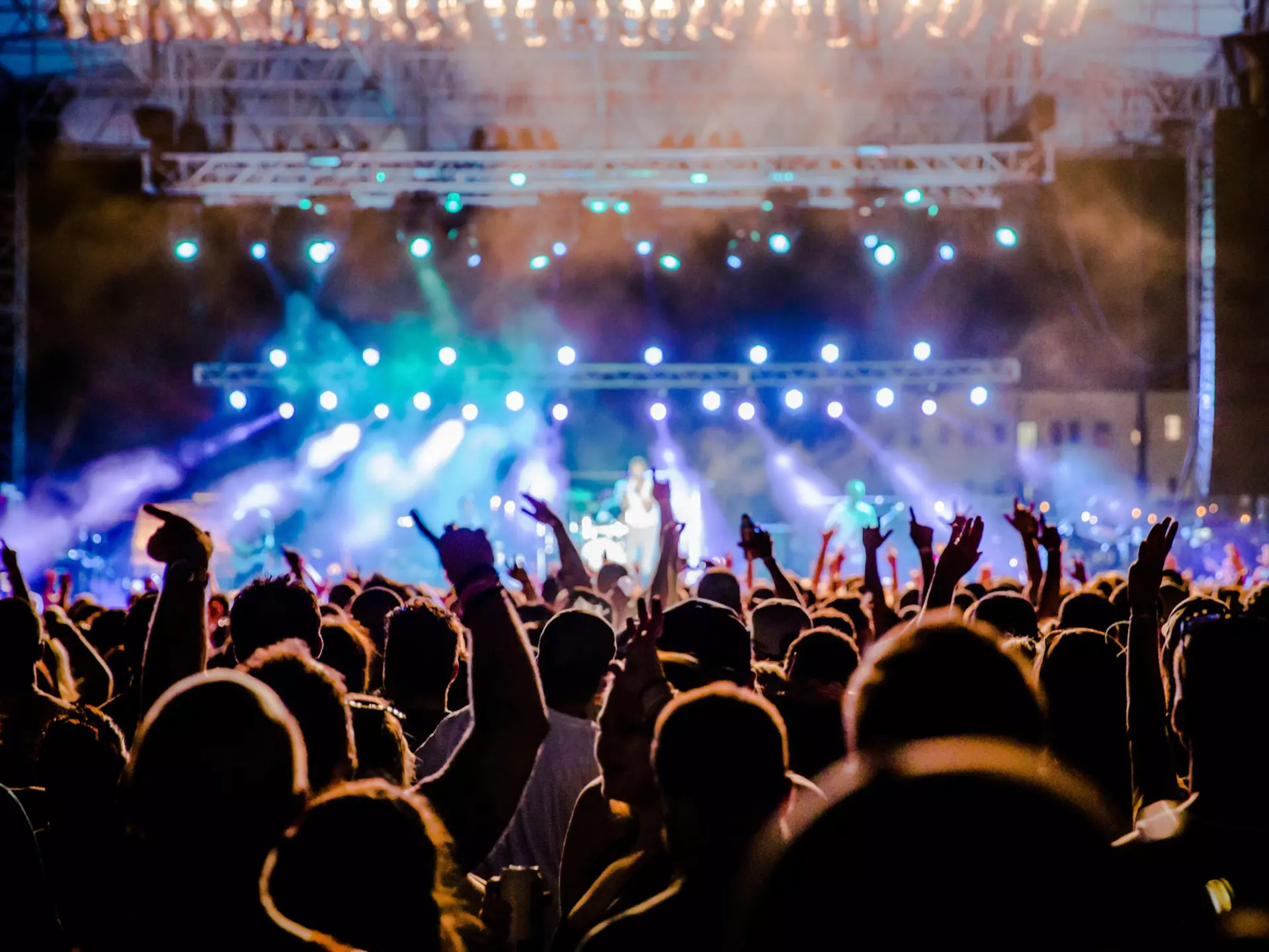 A view towards the stage over the heads of festival goers at night