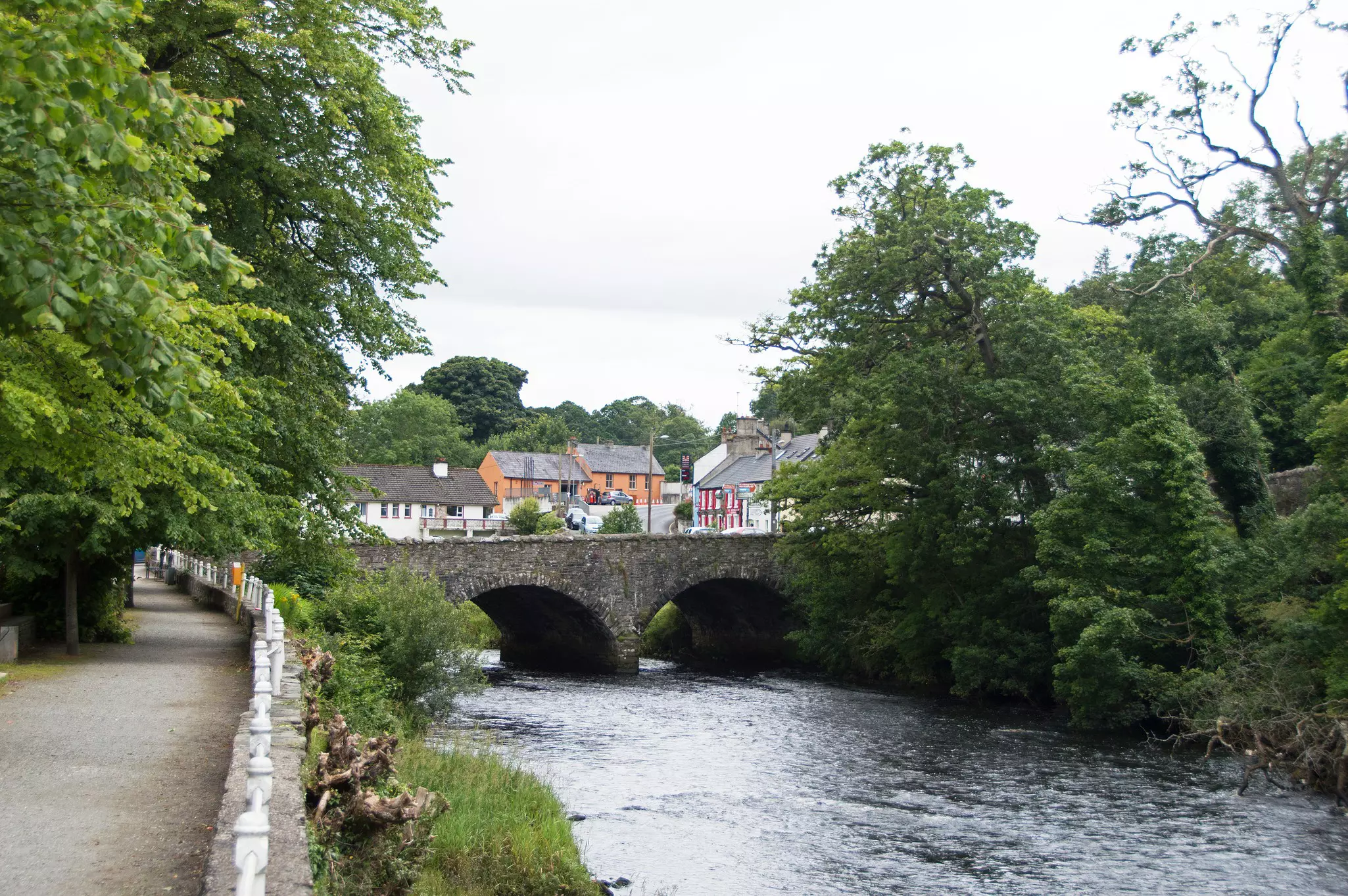 A river runs under a stone bridge with a small village on the other side.