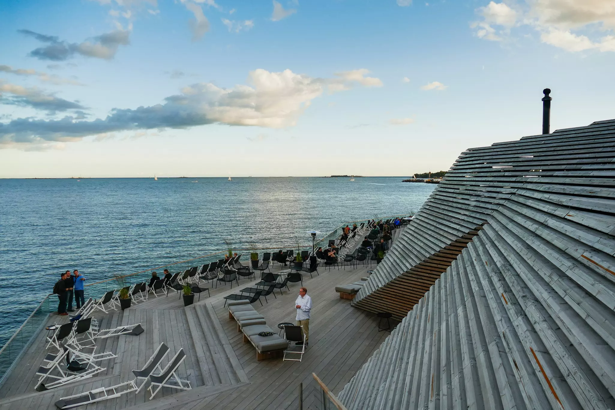A large deck beside the water at a sauna.