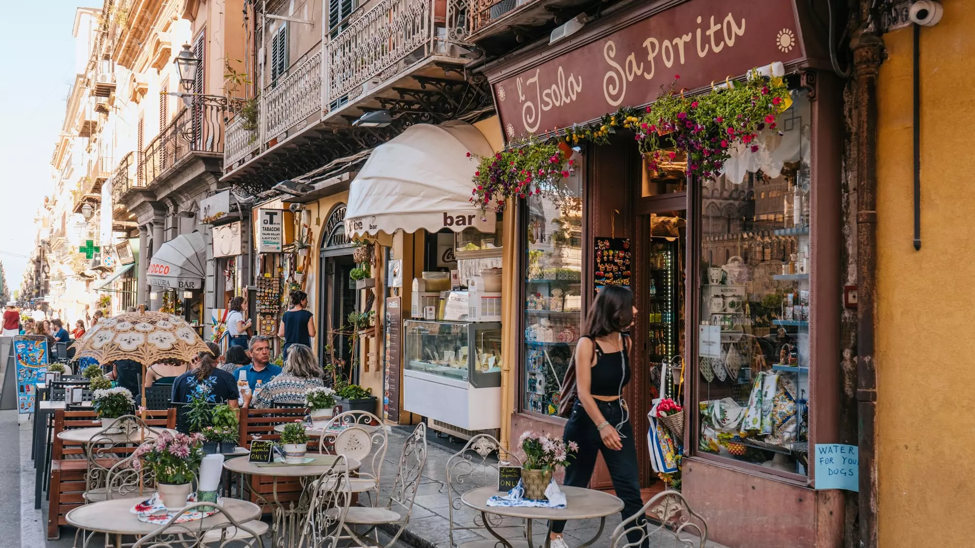 Palermo, Sicily, Italy - May 29 2022: A typical street in the city of Palermo in Sicily, with people sitting outdoors drinking coffee in a cafe bar