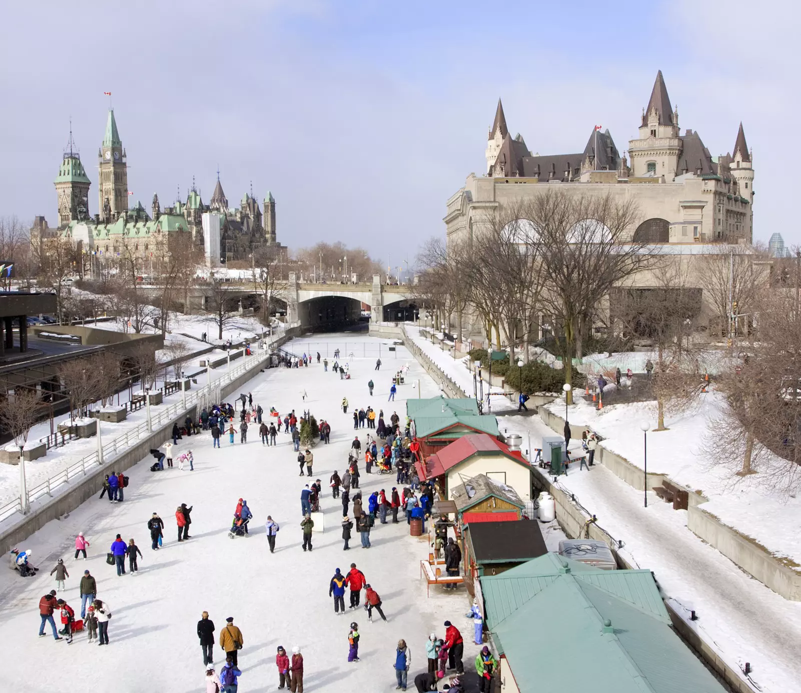 An overhead view of people ice skating on a canal in a city.