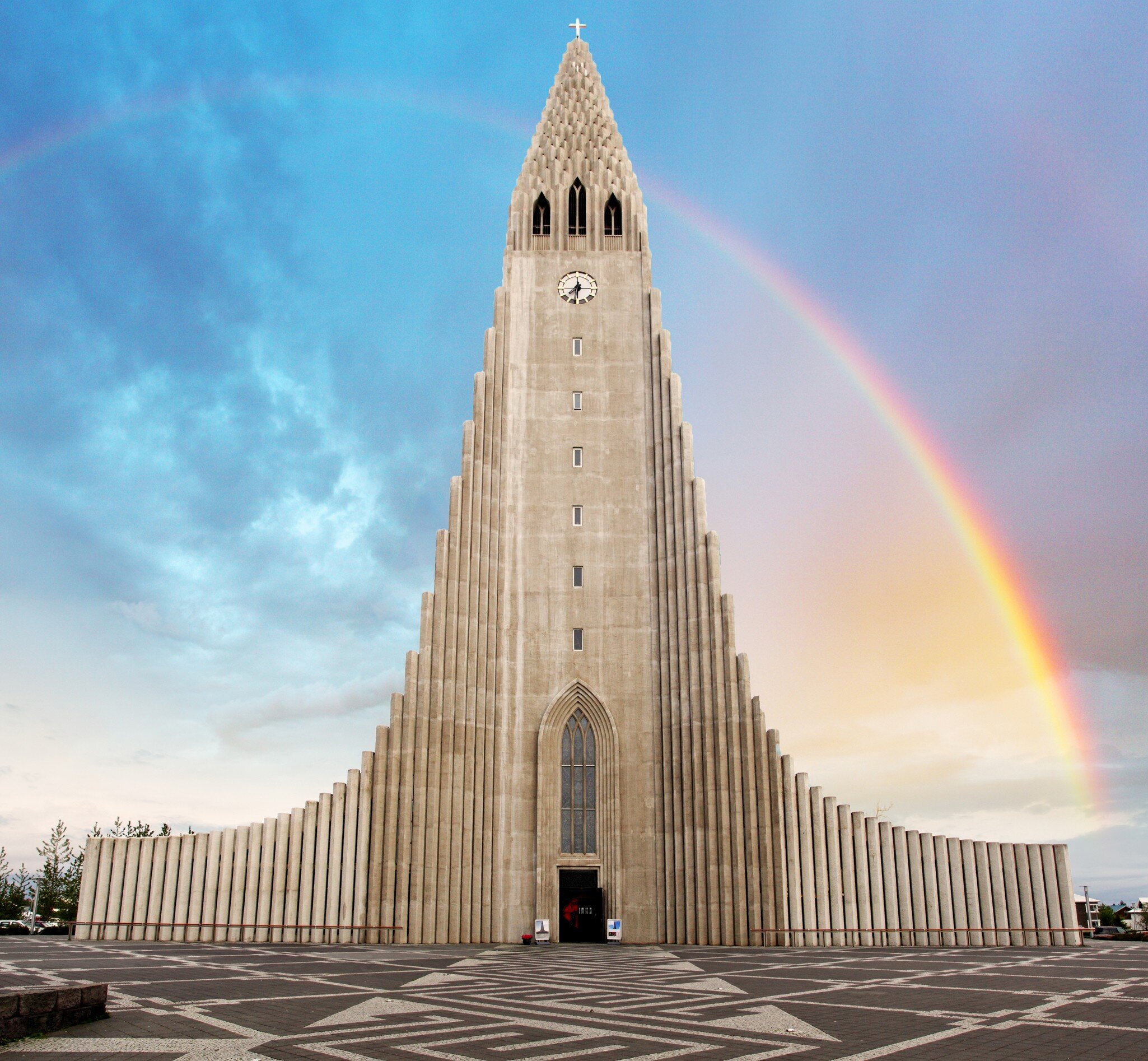 The tall church tower of Hallgrímskirkja in Reykjavík, Iceland, with a rainbow to the side.