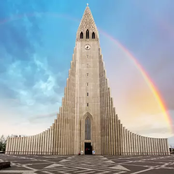 The tall church tower of Hallgrímskirkja in Reykjavík, Iceland, with a rainbow to the side.