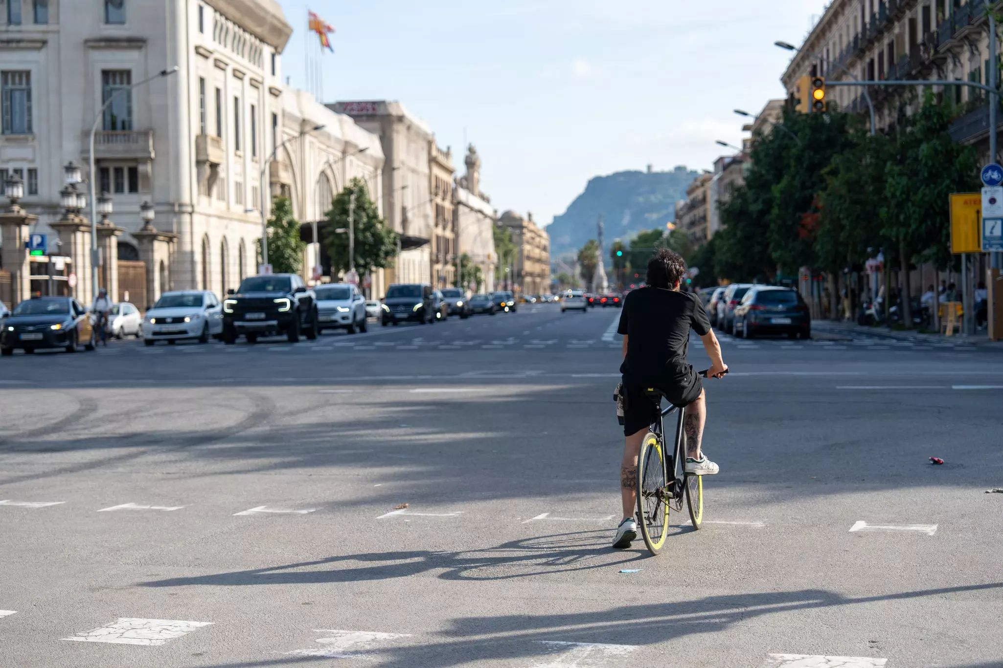 A man cycling on a main street on a sunny day.