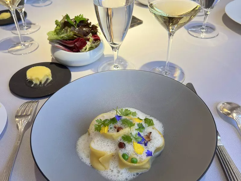 A grey round dish with a pasta in a foamy sauce. 