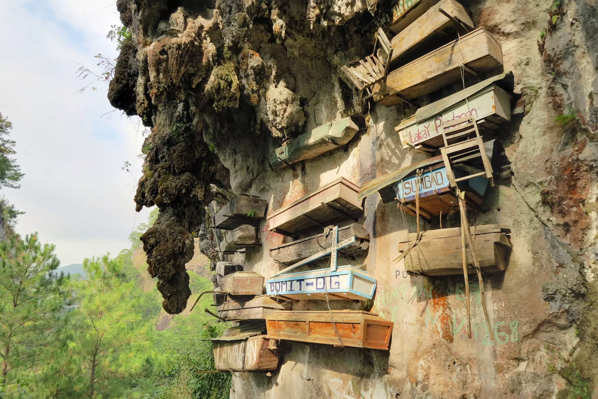 Wooden coffins attached to the side of a cliff face.