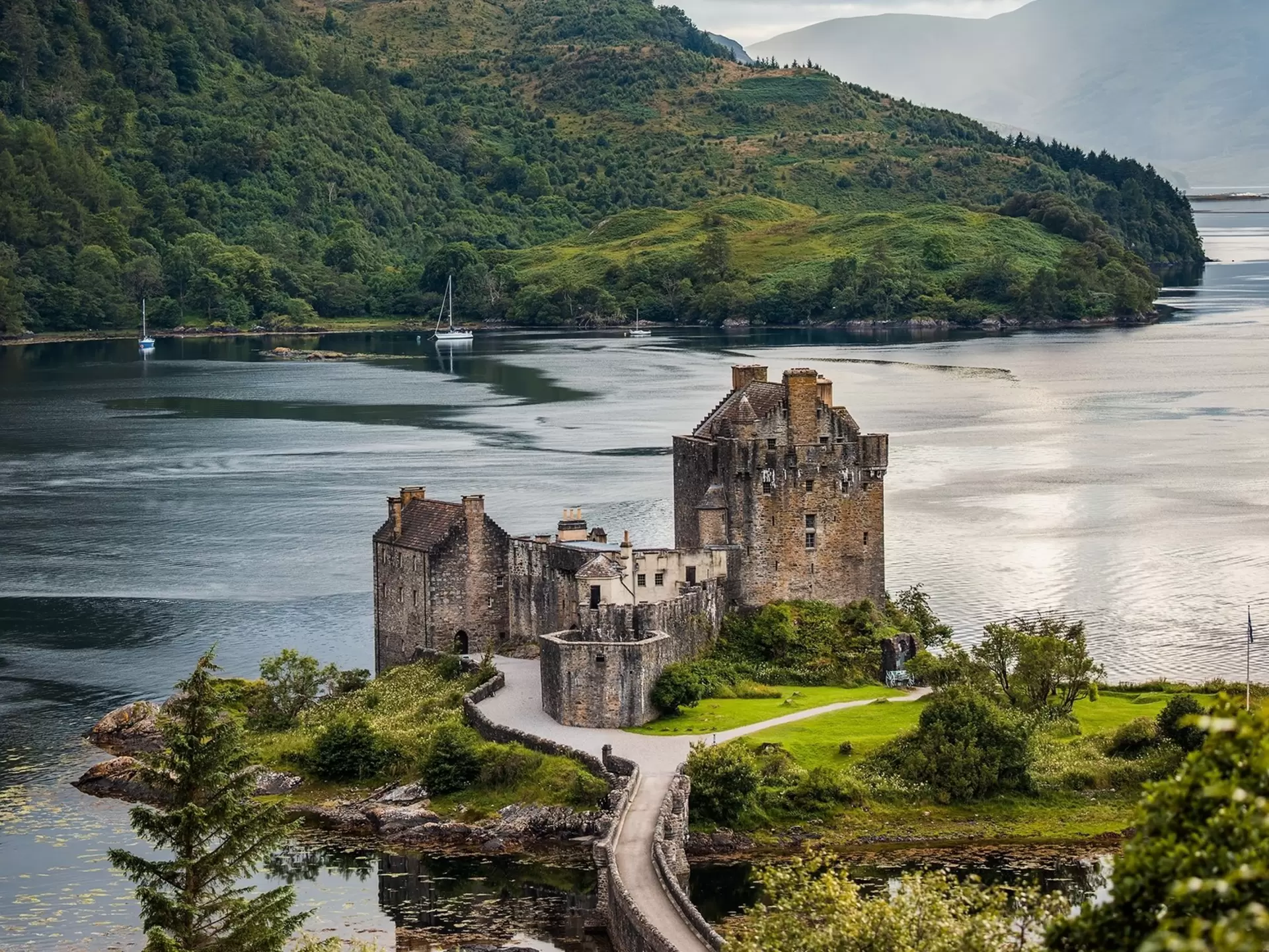 A distance view of Eilean Donan castle, one of the most recognized castles in Scotland, with the loch behind