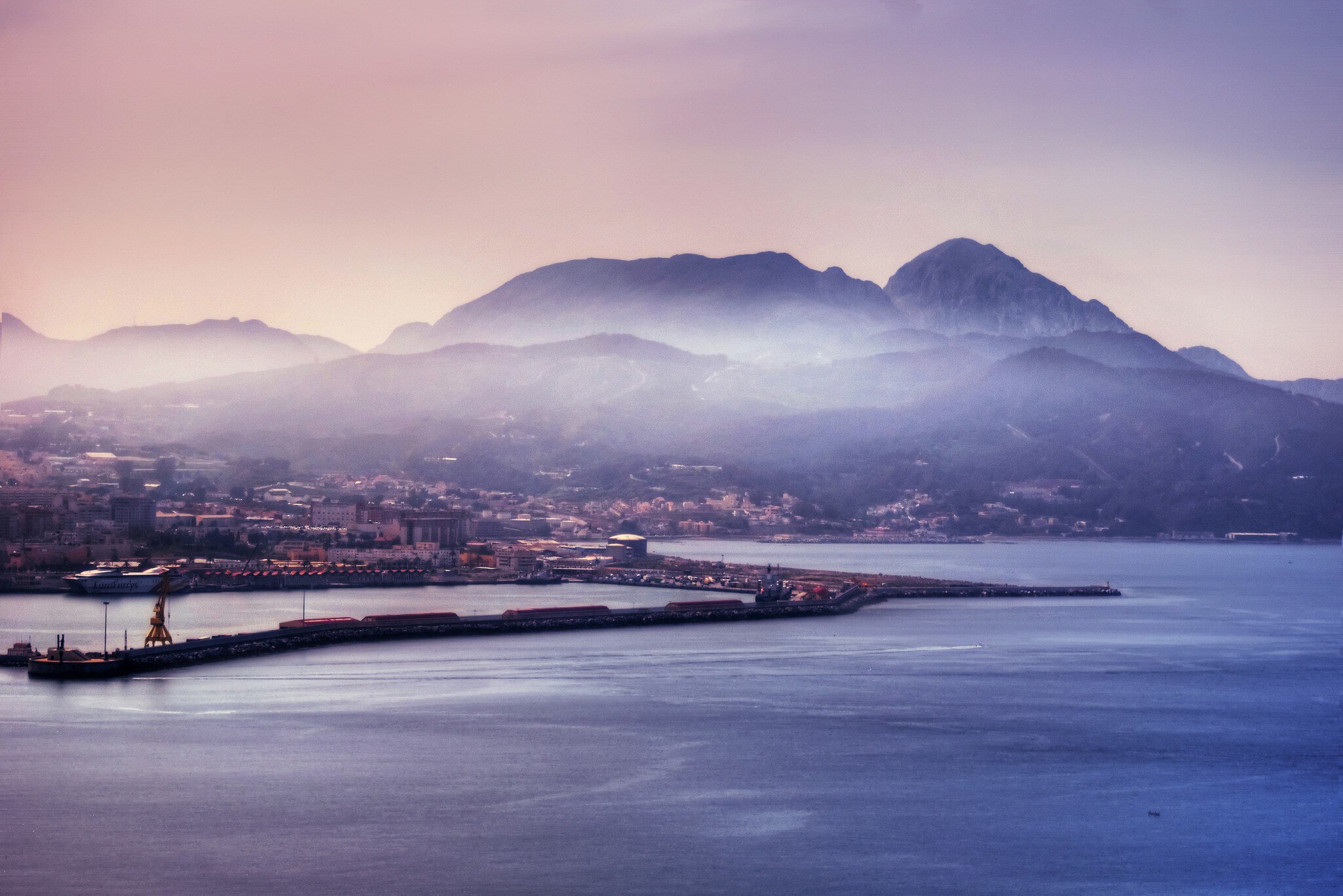 Aerial of the Ceuta harbour with a misty mountain range beyond.