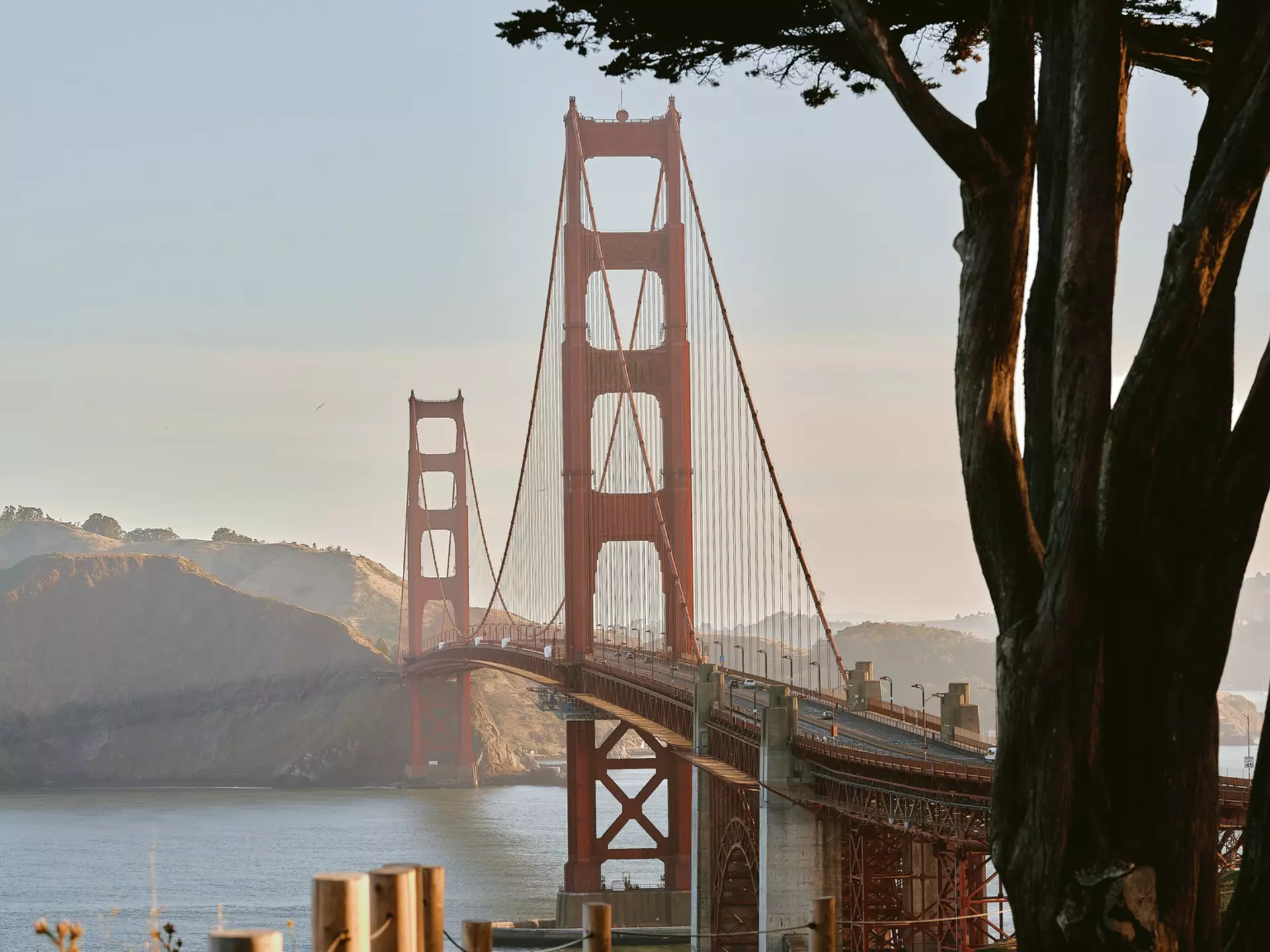 A red suspension bridge in late afternoon light from a shadowed landing.