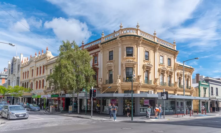 Ornate Victorian-era corner buildings with balustrades and shops, including Polly Shoes, on a Launceston street