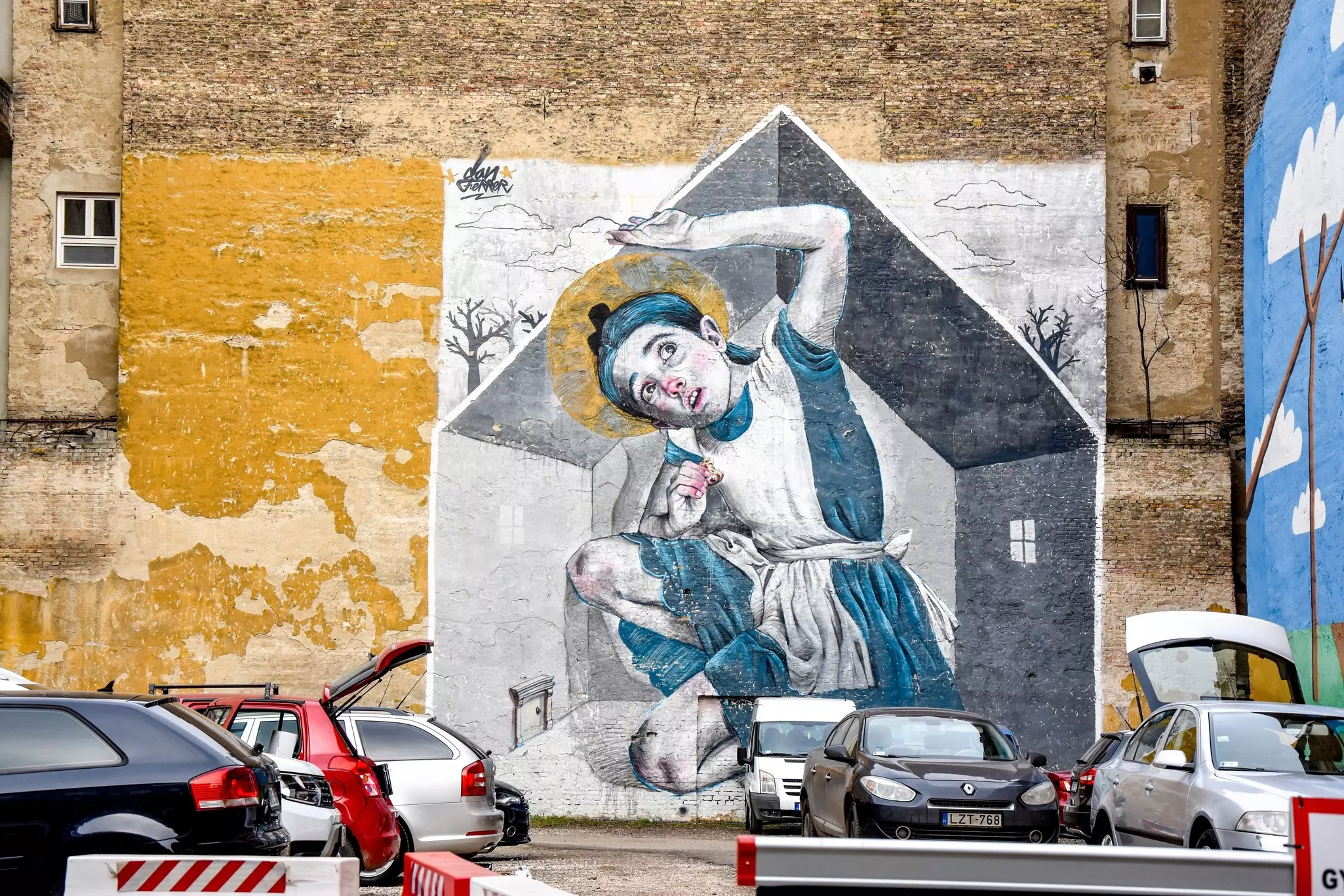 A mural of a young girl filling the space of a house whilst eating a cookie. She reaches above her head as it touches the ceiling of the house.