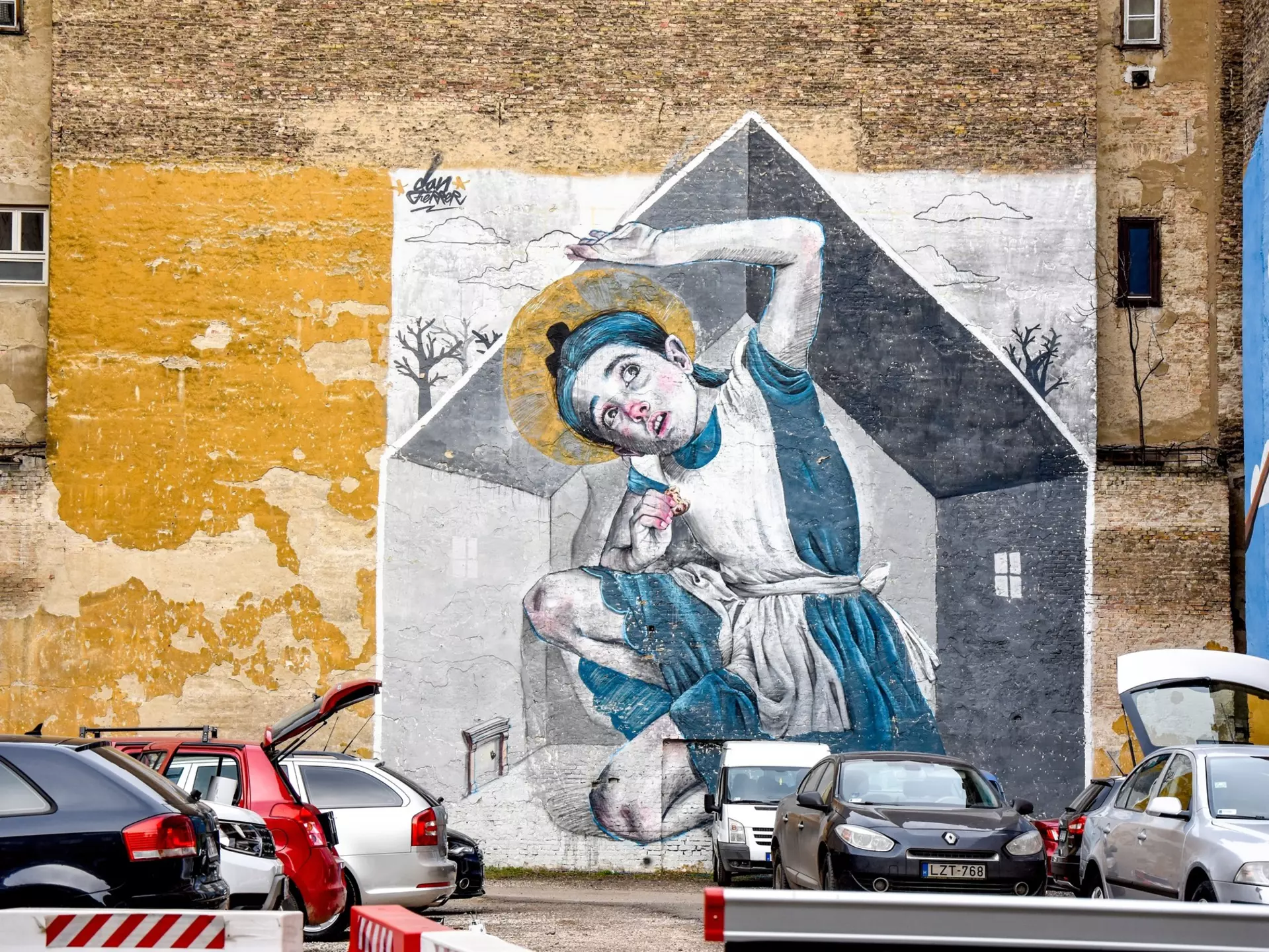 A mural of a young girl filling the space of a house whilst eating a cookie. She reaches above her head as it touches the ceiling of the house.
