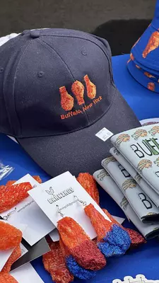 Blue hat embroidered with an orange chicken wing, life sized chicken wing earrings with glitter and a beer koozie