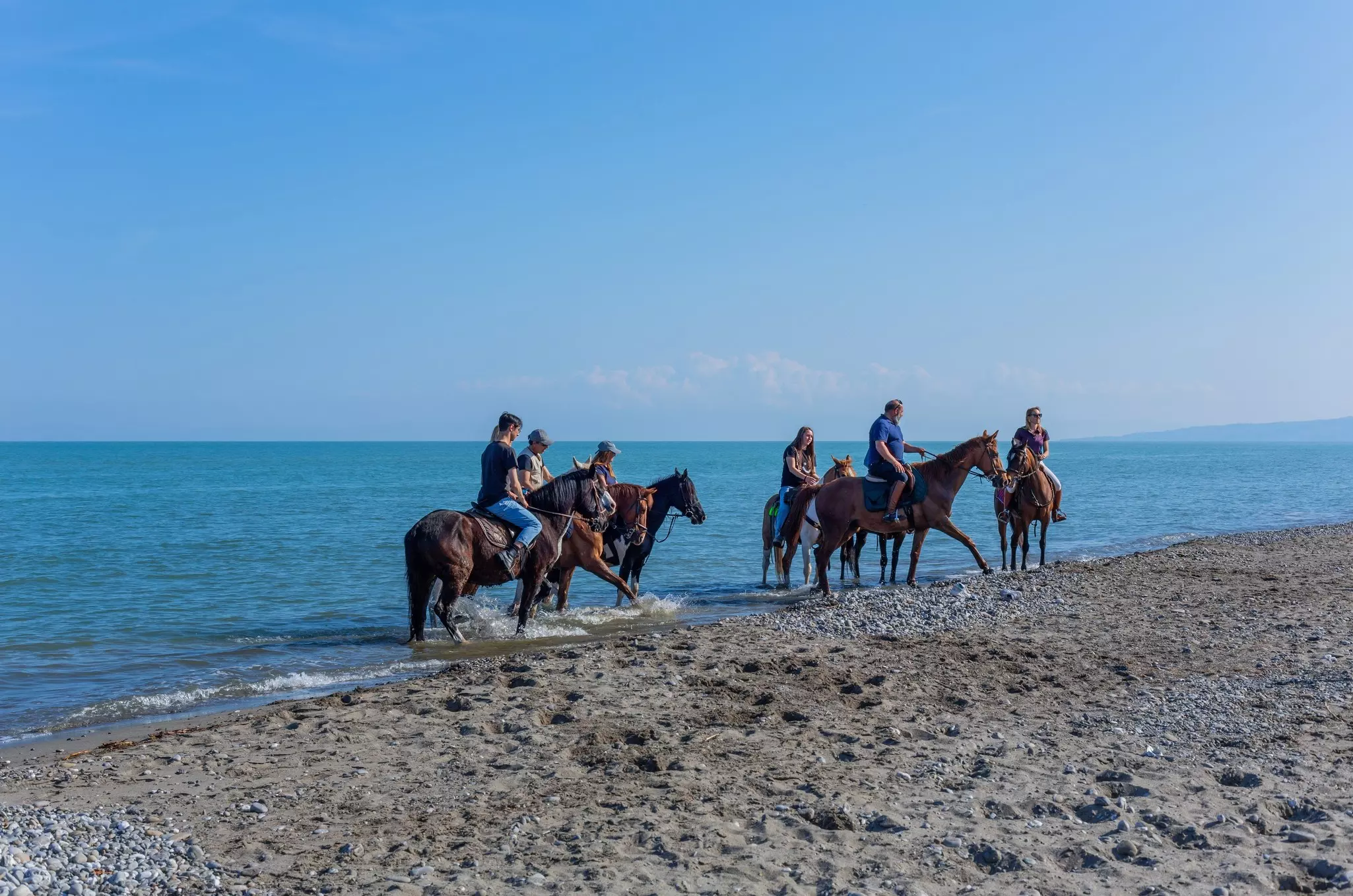 Policoro, Italy - 7 May 2023: People riding horses in a Policoro beach, Basilicata, southern Italy.