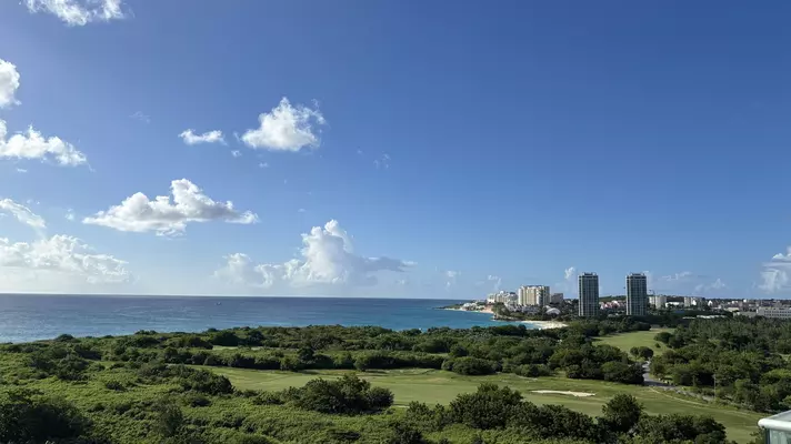 A golf course by the sea with some tall buildings in the distance