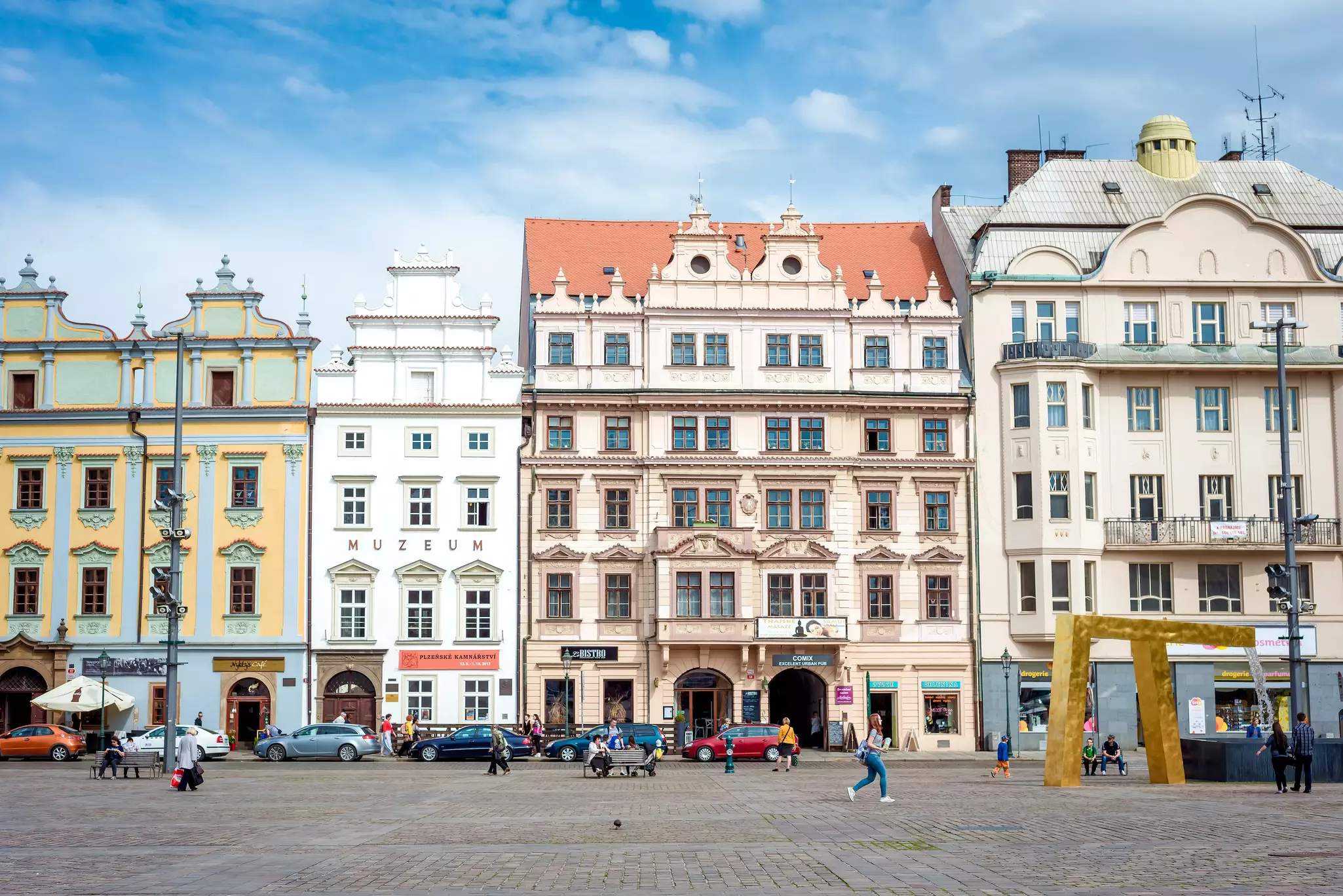 A row of pastel-colored baroque building facades in Plzeň, Czechia.