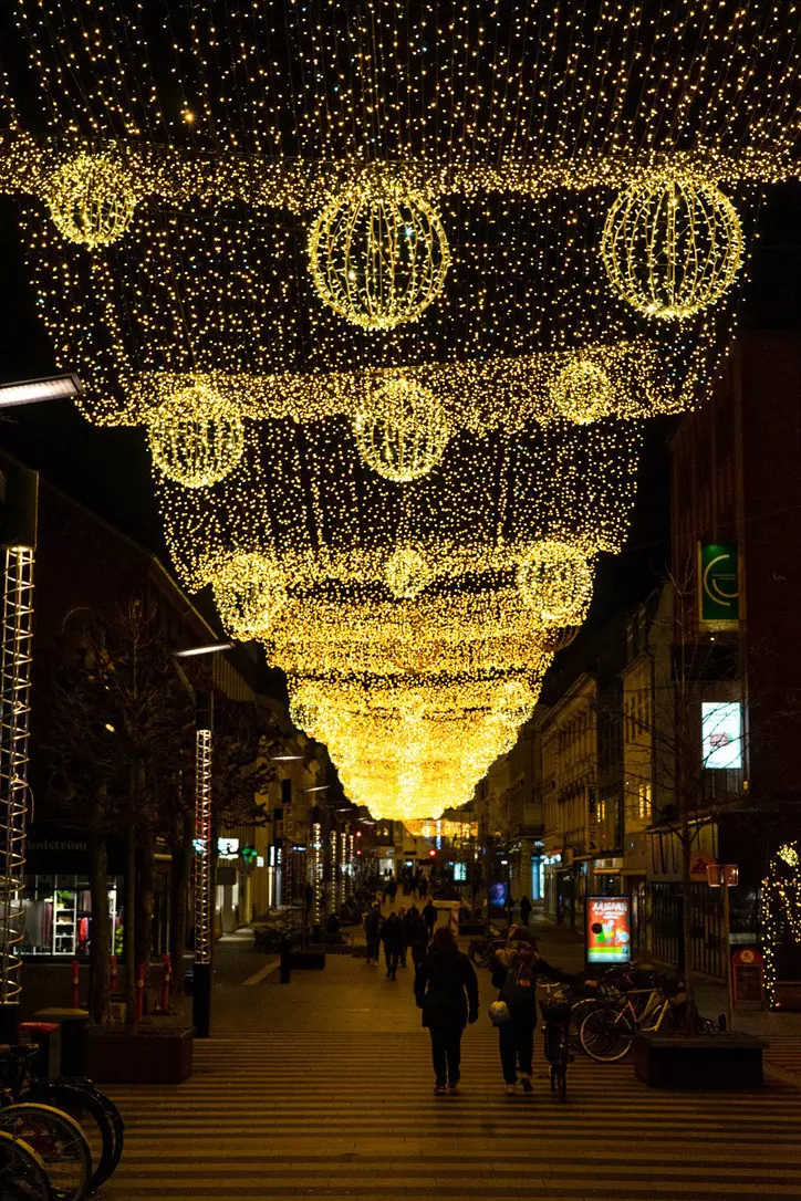 People walking on a street in Aarhus at night that is lit up with fairy lights. A Lonely Planet writer took this image.