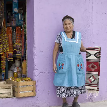 A woman poses with her zapotec rug in front of her shop. solarisimages / Getty Images