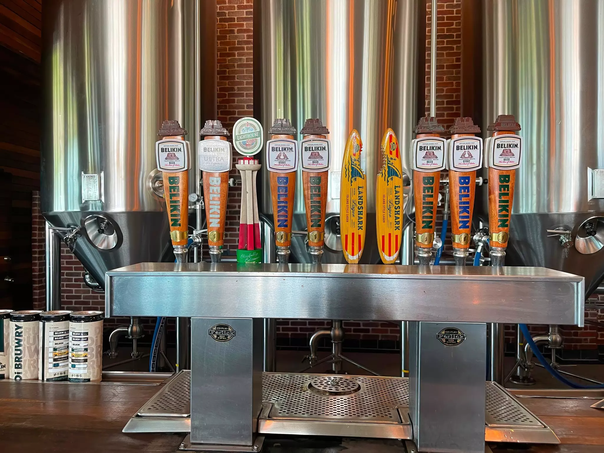 A line of beer tabs inside a brick-walled brewery.