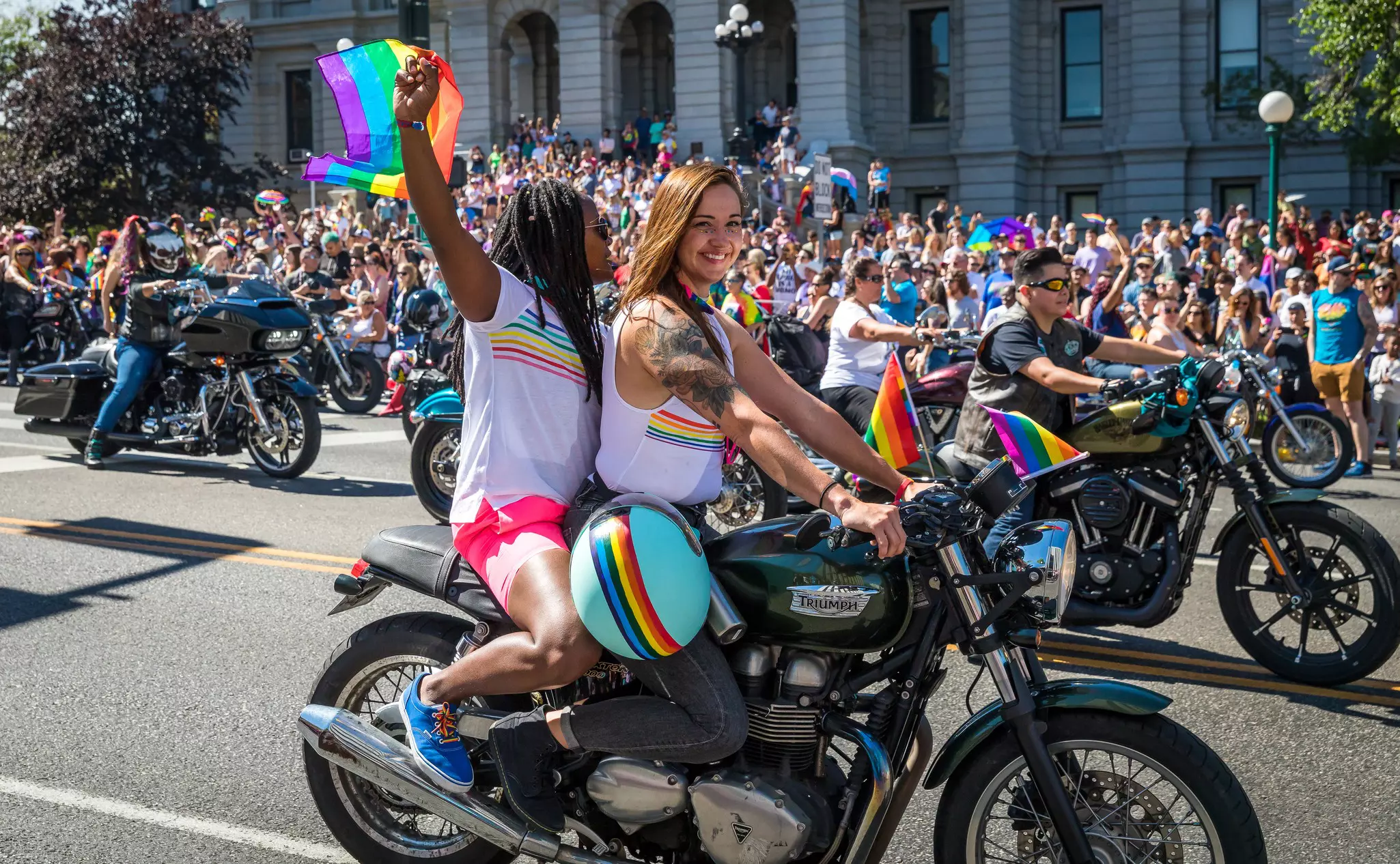 Women on motorbikes at the Denver pride parade waving to crowd