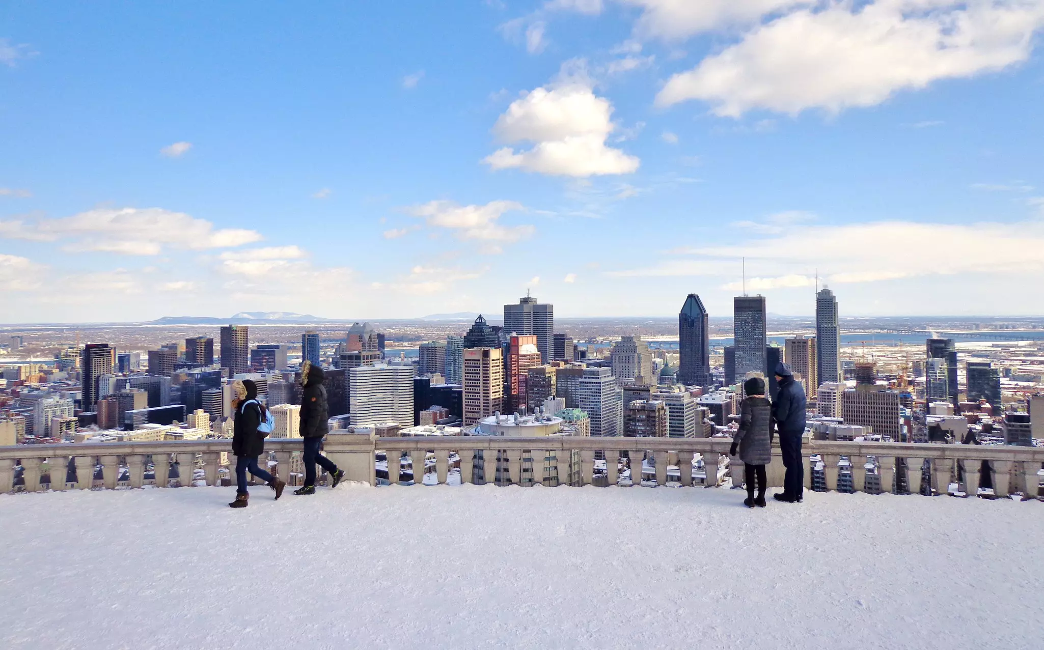 Downtown Montréal with people standing on a balcony overlooking the city on a snow day.