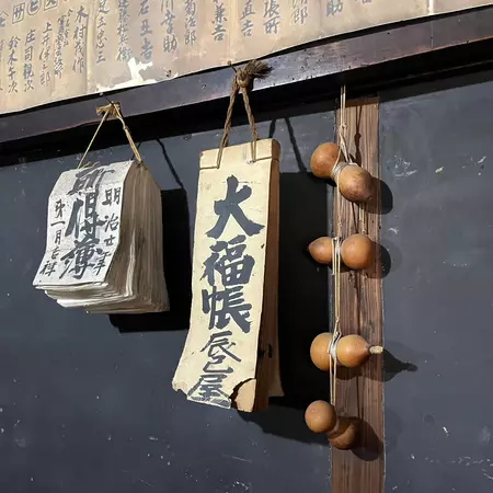 Japanese script on small pads of paper hanging by string on a wall.