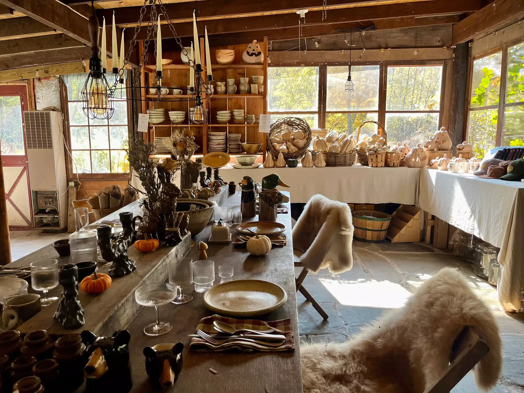 Home goods and animal pelts for sale are displayed on tables in a rustic wooden building.