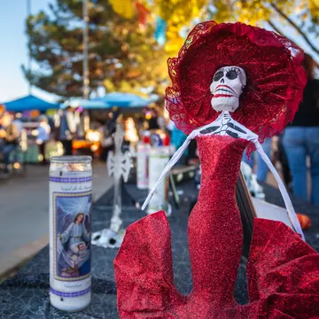 A female skeleton figure called a Catrina in a red dress at the Dia de Los Muertos / Day of the Dead altar in Mesilla, New Mexico