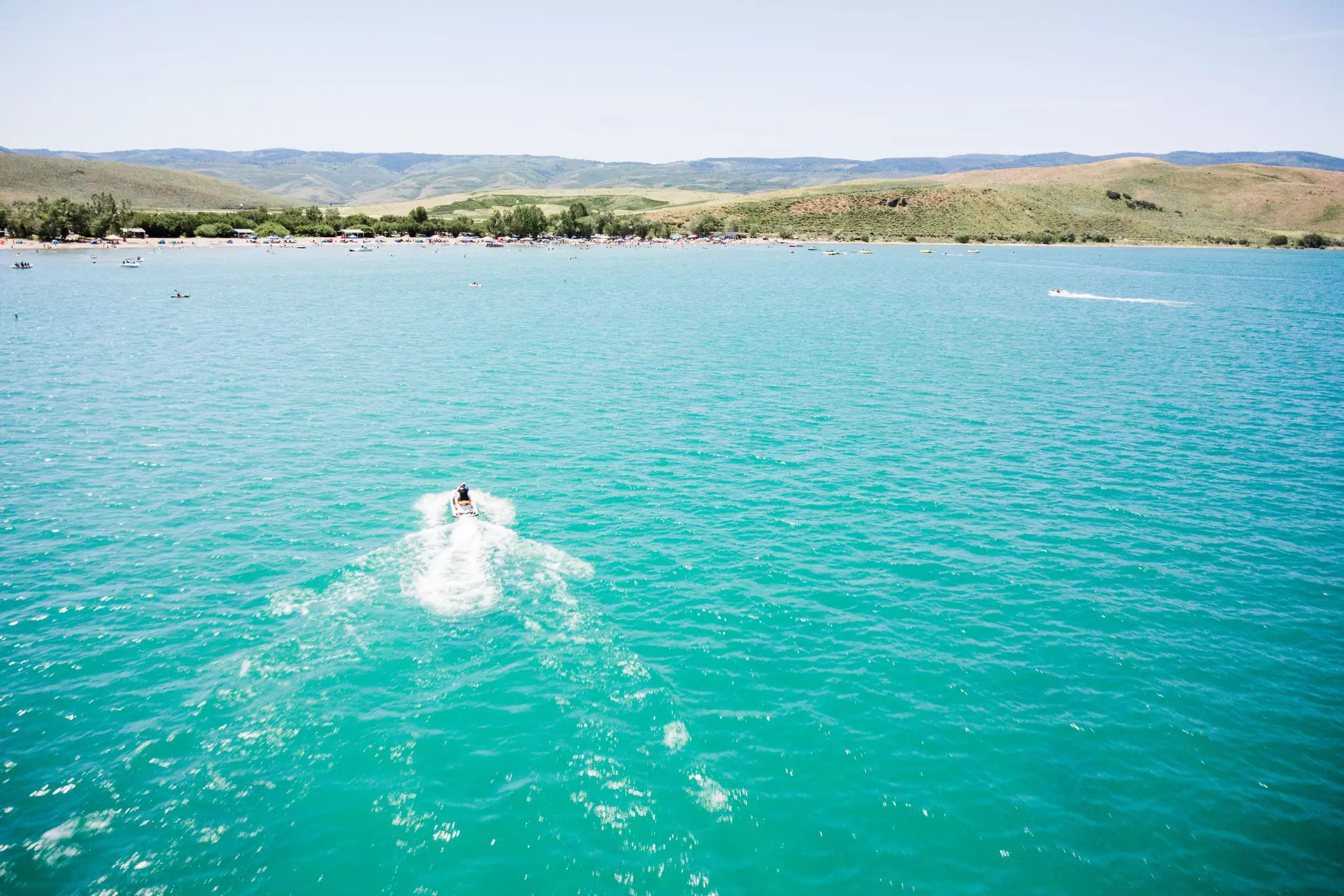 A boat leaves a wake in turquoise water.