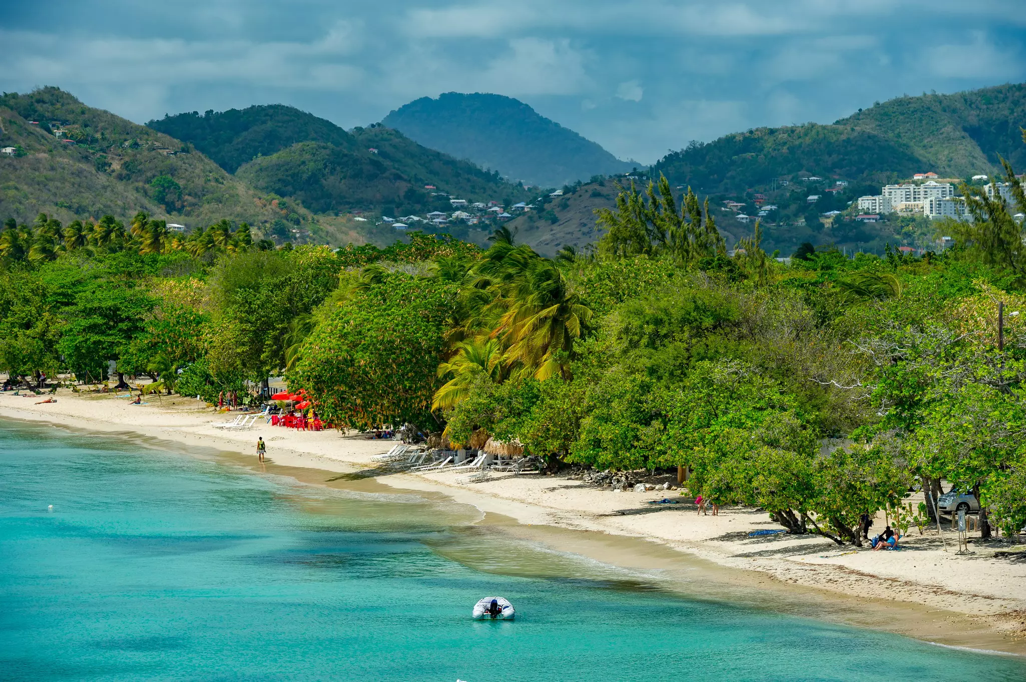 A long white-sand beach backed by thick foliage and lapped by turquoise ocean.