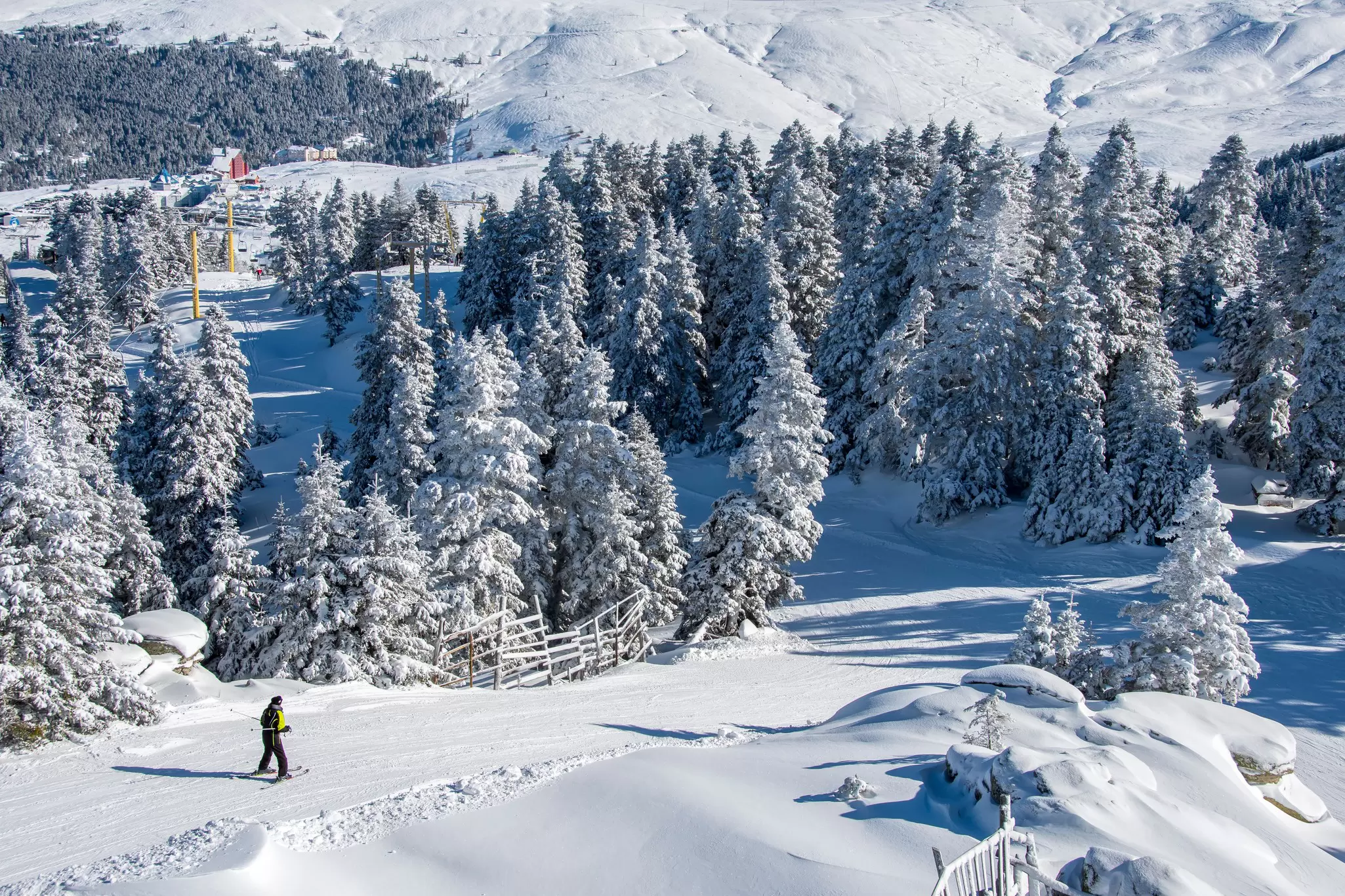 A skiier travels down a snow-covered slope towards dense forest at the Uludağ ski resort in Turkey. 