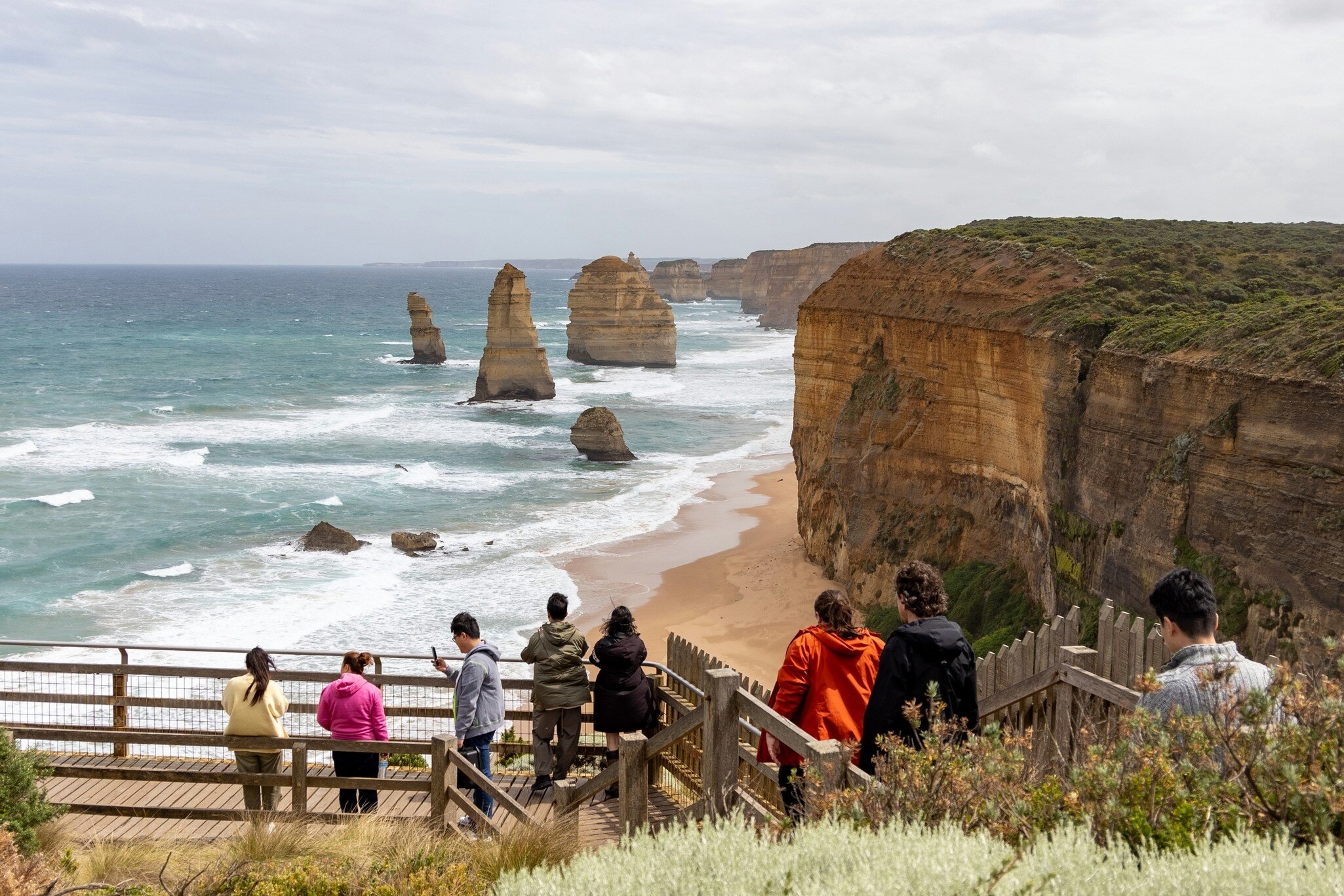 Visitors on a boardwalk overlook the Twelve Apostles limestone stacks and cliffs on the Great Ocean Road, Victoria