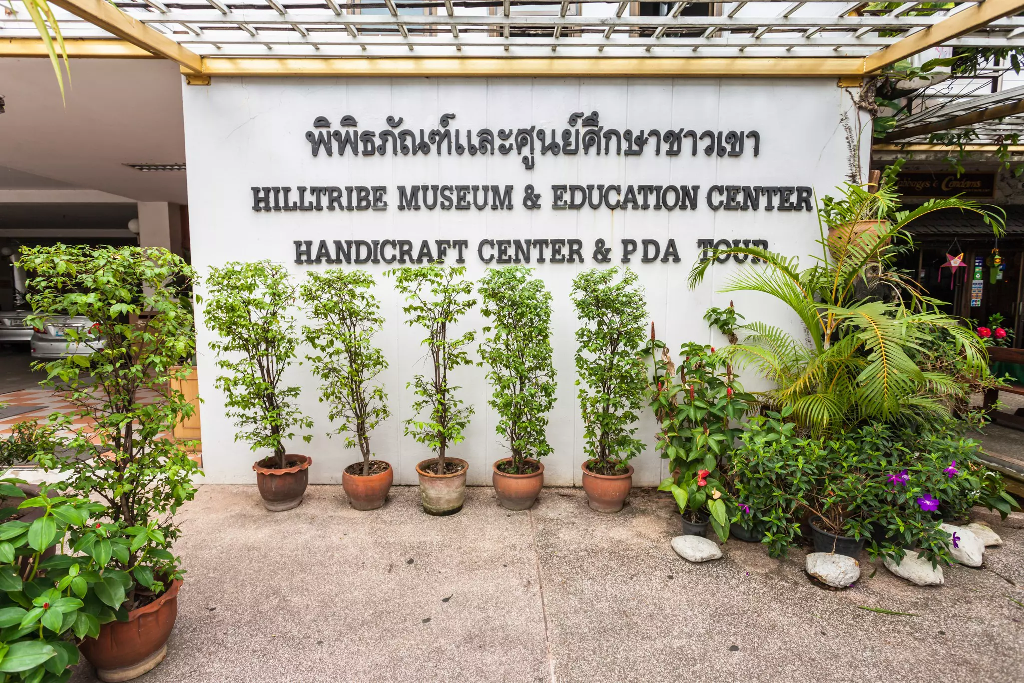 Potted plants frame the front of the Hill Tribe Museum & Education Center in Chiang Rai, Thailand.