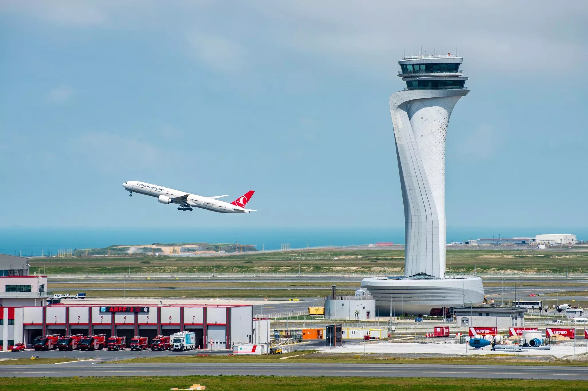 Turkish Airlines airplane taking off with Air Traffic Control Tower to the left at Istanbul Airport. 