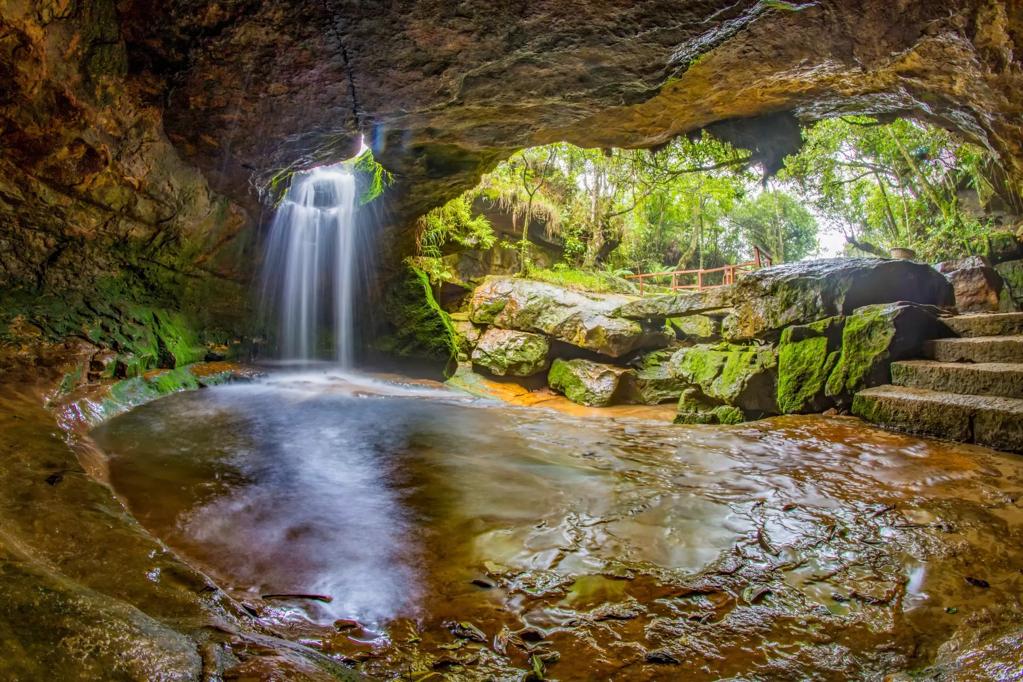A waterfall pours through the hole in a cave roof.