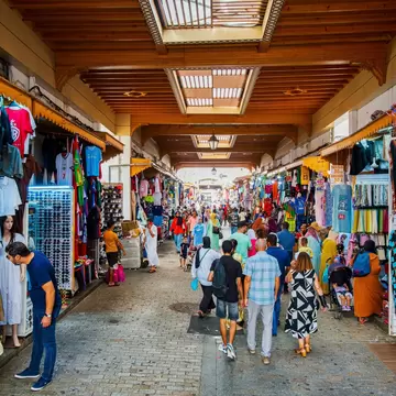 People shopping in a covered market selling clothes.