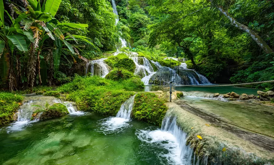 Mele Maat Cascades in Vanuatu: tiered waterfalls and green pools in dense rainforest, with a rope handrail