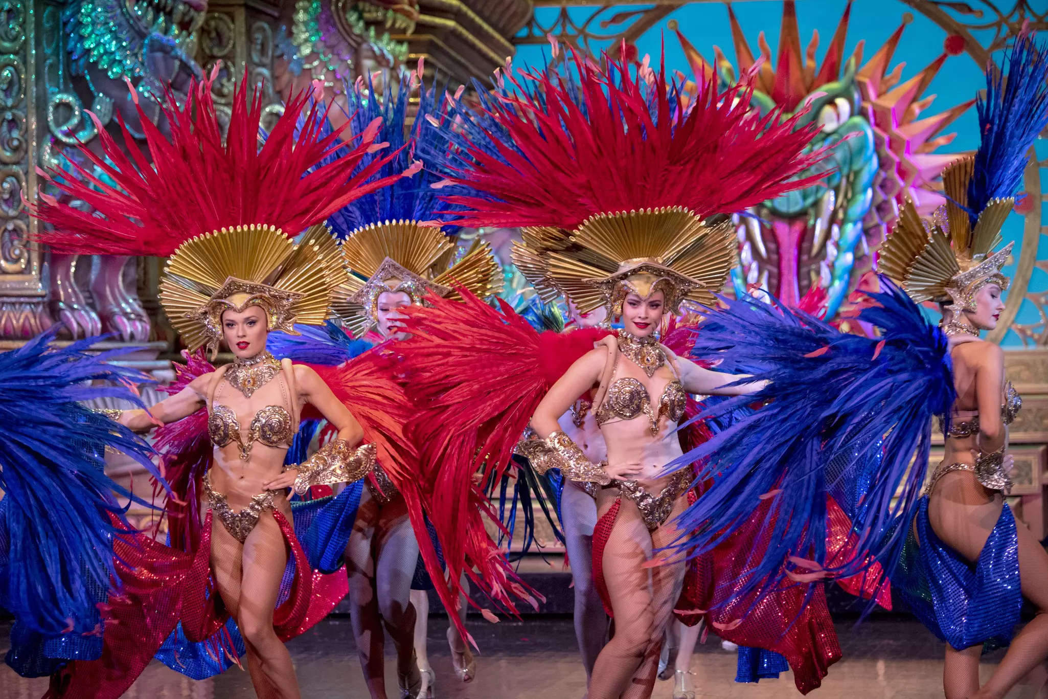 Moulin Rouge dancers in shiny bikini-like outfits and headdresses