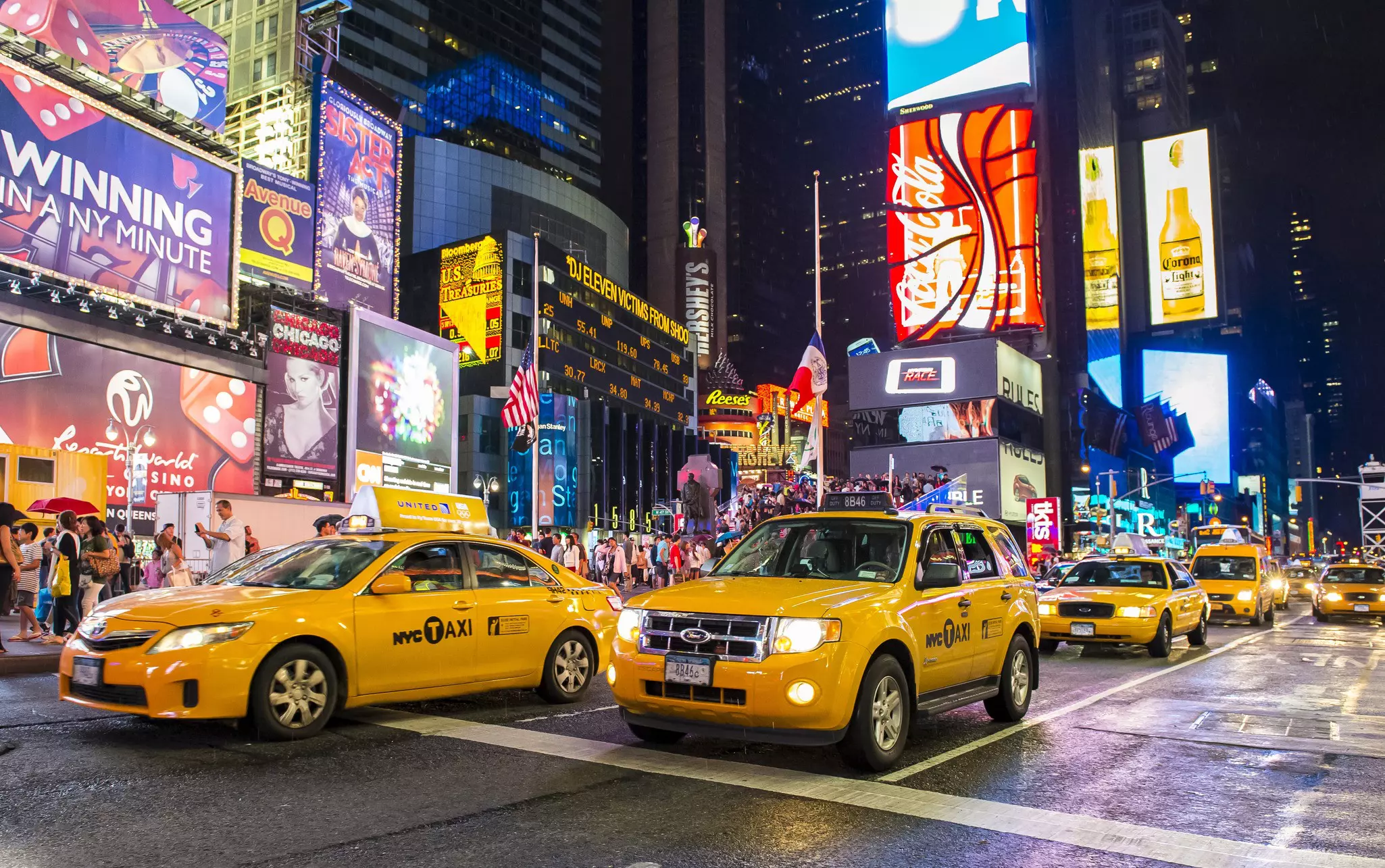 Yellow cabs traveling through Times Square at night