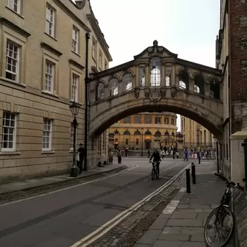 A man rides a bike under an enclosed bridge in Oxford, England. 