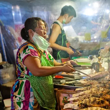 CHIANG MAI, THAILAND - AUGUST 27: Food vendor cooks fish at the Saturday Night Market (Walking Street) on August 27, 2016 in Chiang Mai, Thailand., License Type: media, Download Time: 2026-02-09T09:25:05.000Z, User: claramonitto, Editorial: true, purchase_order: 56530 - Guidebooks, job: Global Publishing-WIP, client: Thailand 20, other: Clara Monitto