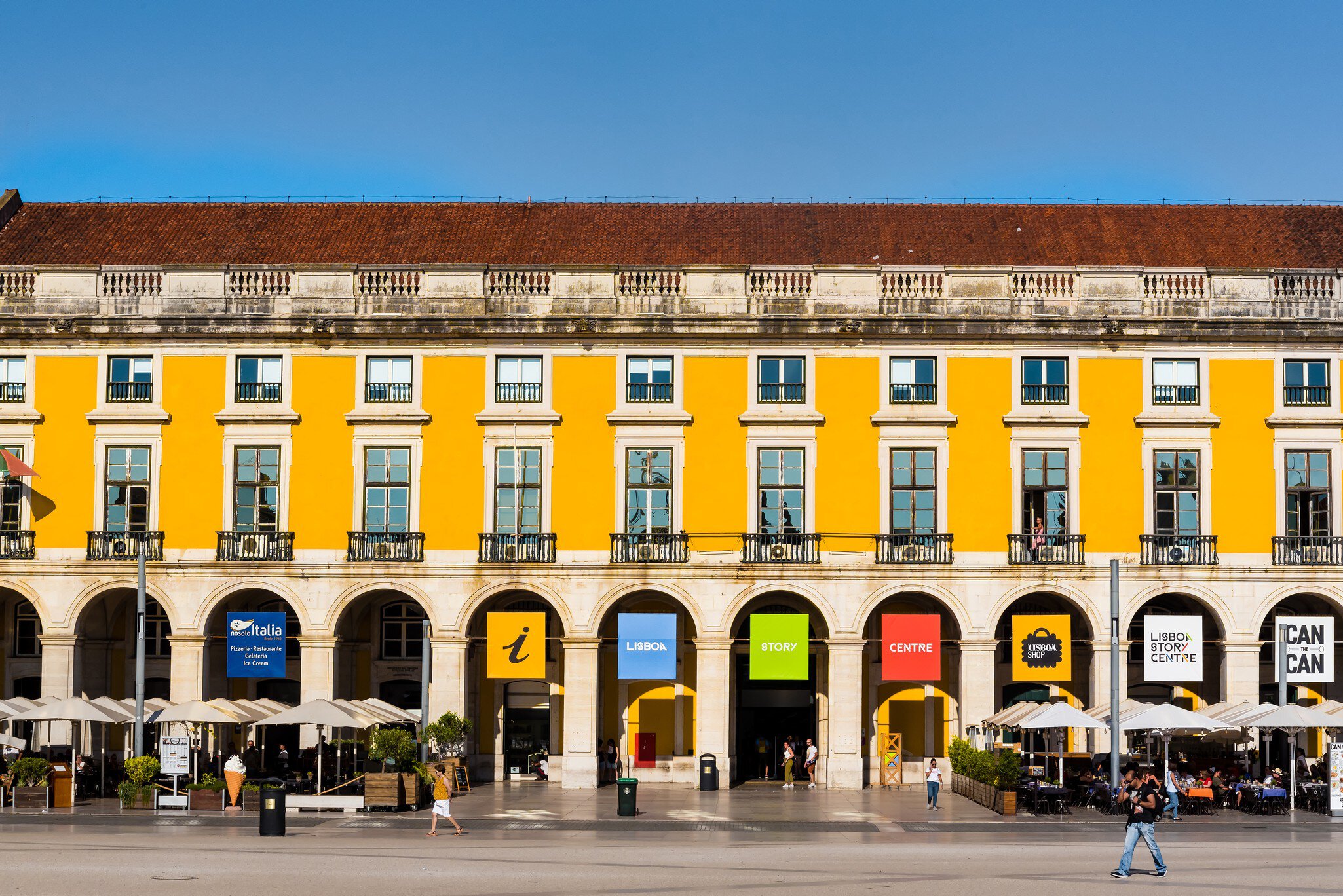 Praça do Comércio, a waterside public plaza in Lisbon with a notable arch & statue, lined with outdoor cafes & shopping venues.