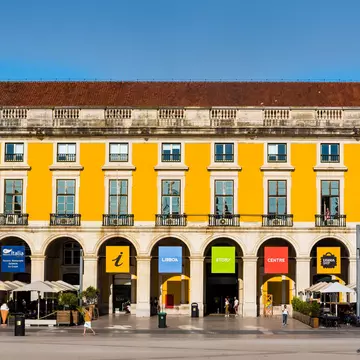 Praça do Comércio, a waterside public plaza in Lisbon with a notable arch & statue, lined with outdoor cafes & shopping venues.