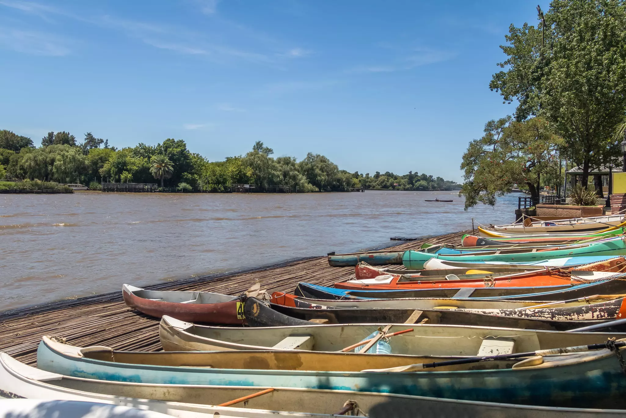 Colorful rowboats on the shore by a brown river in Argentina.