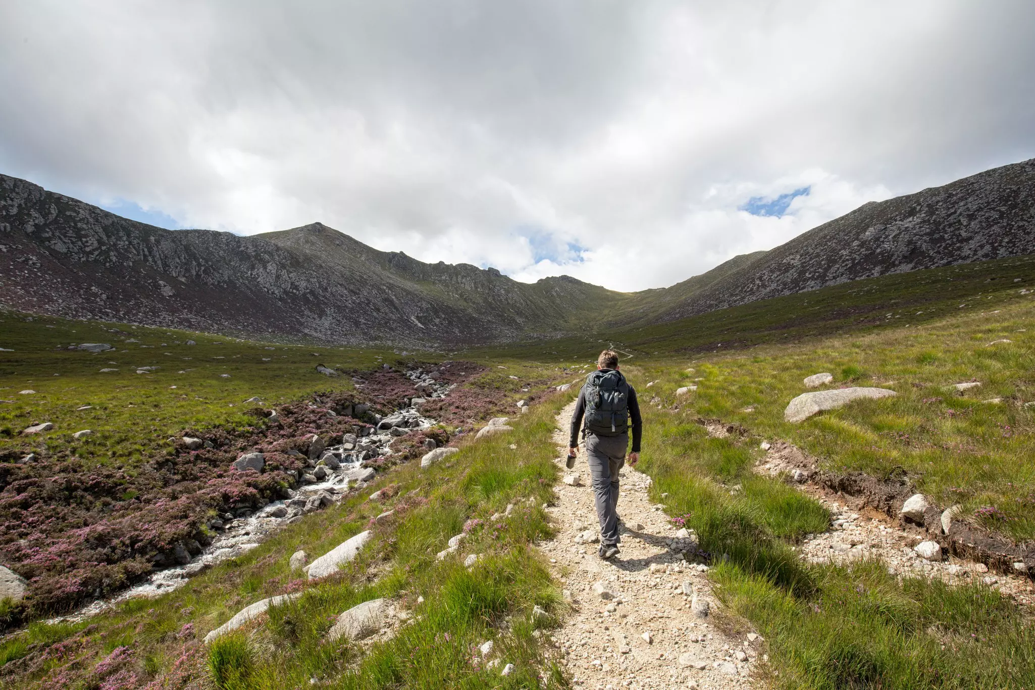 Man hiking through lush mountain valley in Scottish Highlands, Isle of Arran, Scotland.