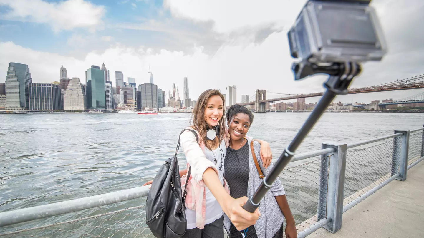 Two women taking a selfie with the New York skyline in the background