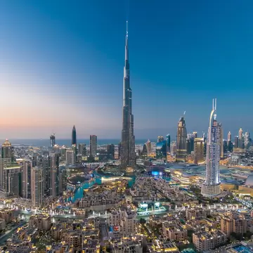 Aerial view of a dense city at dusk with a tapering supertall tower.