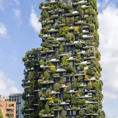 Two tall towers in Milan, with green plants growing on the balconies and exterior.