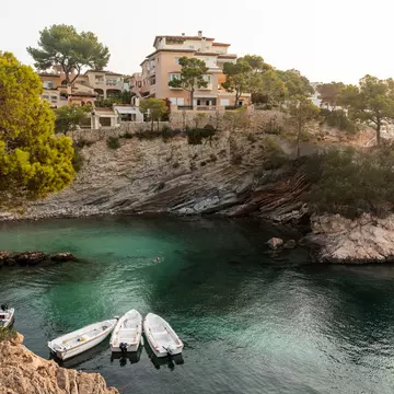 Small boats anchored in a secluded cove surrounded by rocky cliffs and greenery.